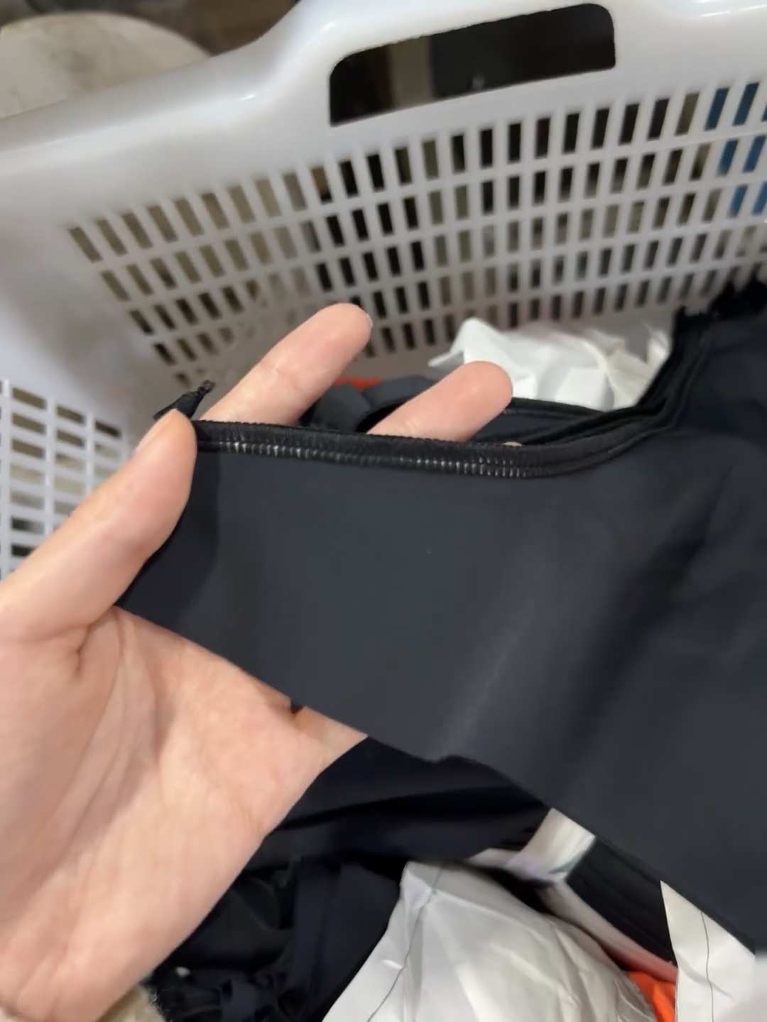 Hands examining the edge finish of a black garment